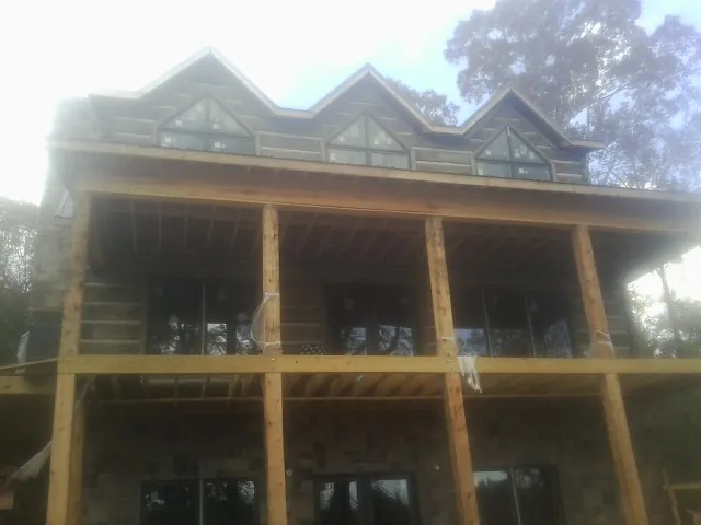 Dormers and porch framing on a large log home under construction — Roof Coating work by our crew in Hinckley